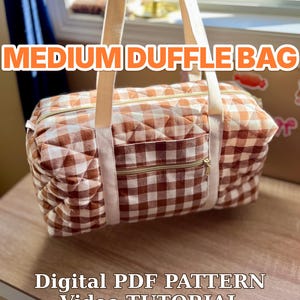 May include: A quilted duffle bag with a brown and white gingham pattern, featuring two cream-colored fabric handles, a front zippered pocket, and gold-tone hardware. Text on the image reads: MEDIUM DUFFLE BAG, Digital PDF PATTERN, Video TUTORIAL, US Letter + A4.