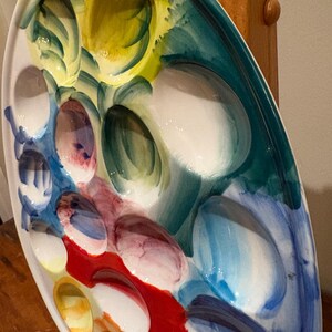 May include: Oval ceramic serving platter with multiple oval compartments. The platter is hand-painted with a colorful design featuring shades of yellow, green, blue, red, and white. The design is abstract and artistic, with brushstrokes visible.