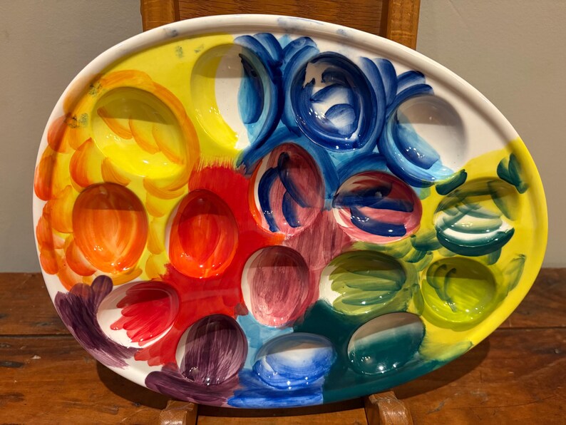 Pu&ograve; includere: Un vassoio da portata in ceramica ovale e colorato, con pi&ugrave; scomparti a forma di uovo. Il vassoio &egrave; dipinto con tonalit&agrave; vivaci di giallo, arancione, rosso, blu, verde e viola. Il design &egrave; artistico e accattivante, perfetto per servire antipasti.