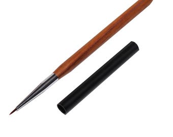 May include: A fine-tipped art brush with a wooden handle and a black protective cap. The brush has a silver ferrule and a dark brown bristle tip, ideal for detailed painting or nail art.