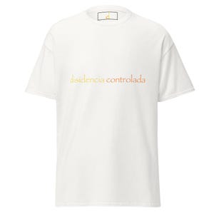 May include: White t-shirt with the text "disidencia controlada" in orange and yellow gradient lettering. The shirt has a crew neck and short sleeves. A small logo is visible on the collar.