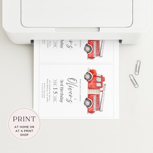 May include: A printer is shown printing two invitations. Each invitation features a watercolor illustration of a red fire truck. The text on the invitation reads "Oliver's 3rd Birthday" and includes the date, time, and location.