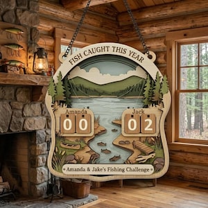 Puede incluir: Letrero de desafío de pesca de madera con el texto "FISH CAUGHT THIS YEAR". El letrero presenta una escena de lago con árboles, montañas y un río. Incluye espacios para rastrear capturas para "Amanda" y "Jack".