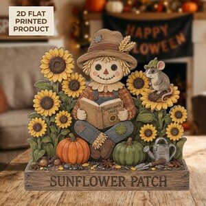 Peut inclure: Une décoration de table imprimée à plat en 2D représentant un épouvantail lisant un livre intitulé Sunflower Tales, entouré de tournesols, d'une souris, de citrouilles et d'un arrosoir. La base porte l'inscription Sunflower Patch.