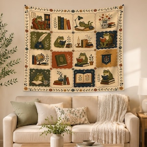 May include: A rectangular wall tapestry featuring a grid of twelve illustrations of frogs reading books, writing with quills, and interacting with library items. The design includes floral borders and a cream background with muted earth tones.