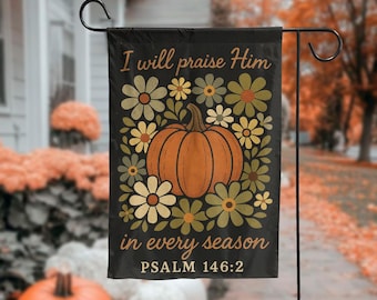 Può includere: Bandiera da giardino nera con un design a zucca e floreale. La bandiera presenta il testo "I will praise Him in every season" e "PSALM 146:2". La zucca è arancione, circondata da fiori verdi, gialli e color crema.