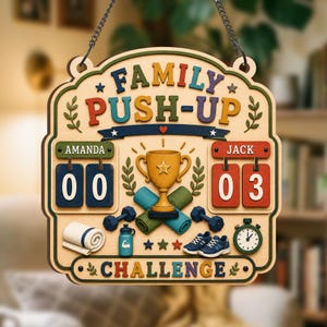 Könnte beinhalten: Ein hölzernes Wandhängeschild mit der Aufschrift FAMILY PUSH-UP CHALLENGE, einem goldenen Pokal in der Mitte, zwei Anzeigetafeln für Amanda und Jack, Hanteln, einer Trinkflasche, einem gerollten Handtuch, Turnschuhen und einer Stoppuhr.