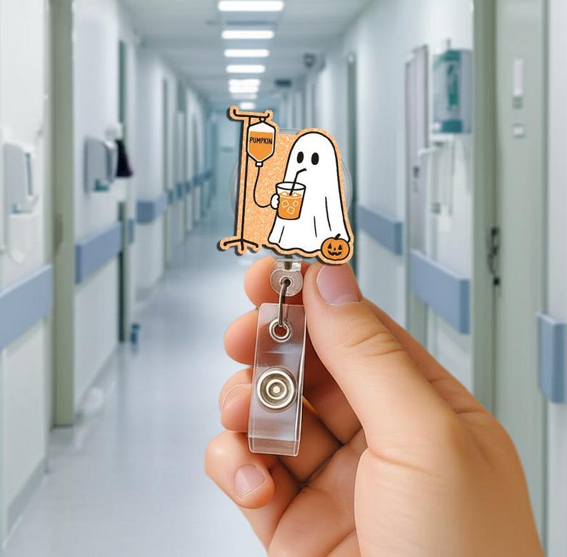 May include: A Halloween-themed badge reel with a cartoon ghost drinking from a cup, a pumpkin, and an IV bag. The badge reel is made of wood and has a clear plastic retractable holder.