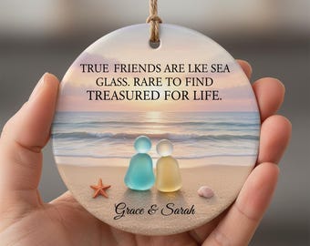 May include: A round ceramic ornament with a beach scene featuring two glass figures, a starfish, and a seashell. The text reads "TRUE FRIENDS ARE LIKE SEA GLASS. RARE TO FIND TREASURED FOR LIFE." The names "Grace & Sarah" are printed below.