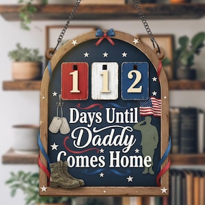 May include: Wooden sign with a dark blue background, featuring the text "Days Until Daddy Comes Home." It includes a countdown with the numbers 112, an American flag, military boots, and dog tags. The sign is decorated with red, white, and blue accents.