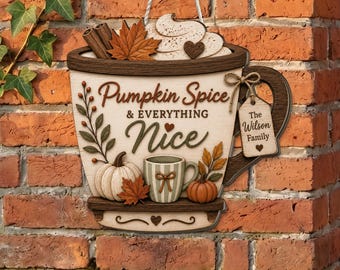Può includere: Una decorazione da parete in legno a forma di grande tazza con il testo Pumpkin Spice & EVERYTHING Nice. Presenta una zucca bianca, una tazza più piccola a righe, bastoncini di cannella, foglie autunnali e un'etichetta con The Wilson Family.