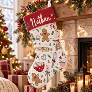 May include: A white Christmas stocking with a red cuff featuring the name Nathan in white script. The stocking is decorated with a repeating pattern of gingerbread men, candy canes, rolling pins, whisks, cupcakes, and mixing bowls.