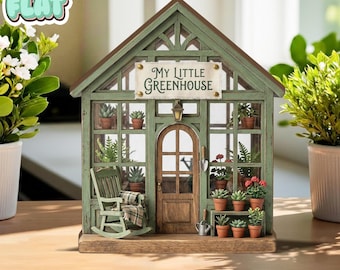 Può includere: Una serra verde in miniatura con tetto e porta marroni. Il cartello recita "My Little Greenhouse". All'interno ci sono piccole piante in vaso, una sedia a dondolo e un annaffiatoio. La serra è un oggetto decorativo.