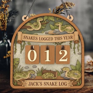 May include: Wooden snake log with a decorative arch design. The sign features illustrations of green snakes, foliage, and the text "Snakes Logged This Year" and "Jack's Snake Log". The numbers "012" are displayed on wooden blocks.