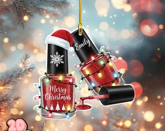 May include: Christmas ornament shaped like nail polish bottles. One bottle has a Santa hat and snowflake, the other has the name "Emily". Both are red with glitter and wrapped in Christmas lights. The text "Merry Christmas" is on one bottle.