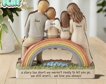 Può includere: Una statuina di famiglia raffigurante un padre, una madre e due bambini, uno con le ali d'angelo, seduti su un arcobaleno. La base riporta la scritta: "a story too short we weren't ready to let you go, we still aren't... we love you always."