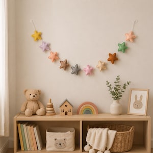 Colorful felt star garland for nursery wall decor with pastel rainbow stars hanging on string, baby room decoration above crib or shelf, soft Montessori nursery decor perfect for kids room and baby shower gift.