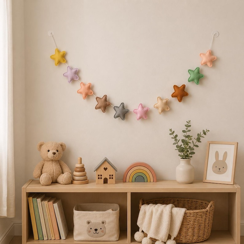 Colorful felt star garland for nursery wall decor with pastel rainbow stars hanging on string, baby room decoration above crib or shelf, soft Montessori nursery decor perfect for kids room and baby shower gift.