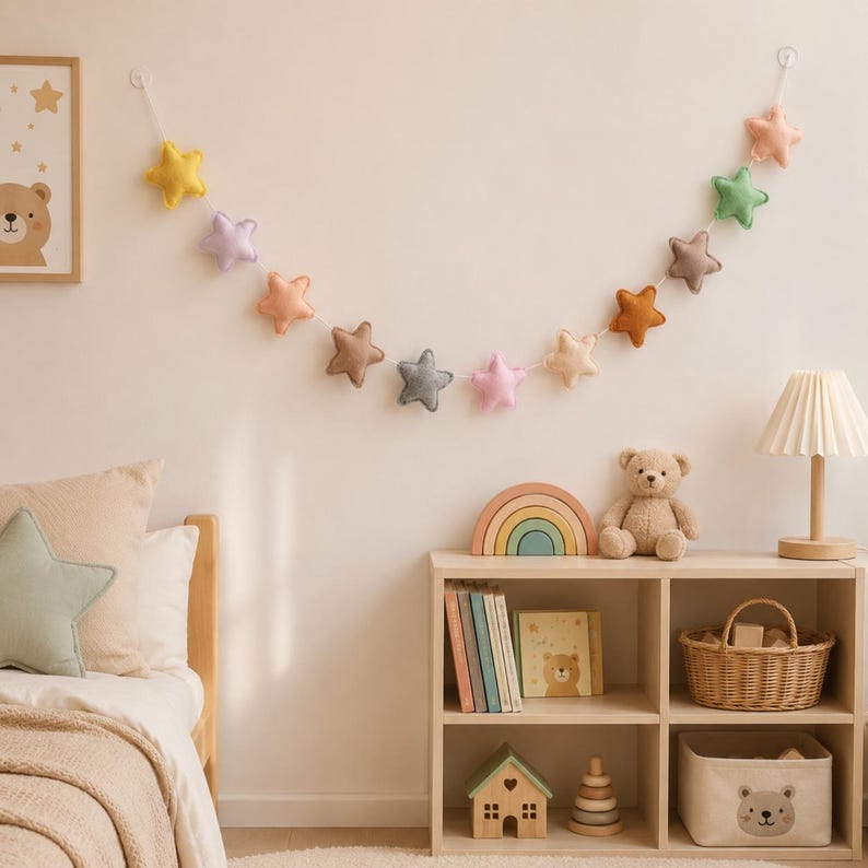 Colorful felt star garland for nursery wall decor with pastel rainbow stars hanging on string, baby room decoration above crib or shelf, soft Montessori nursery decor perfect for kids room and baby shower gift.
