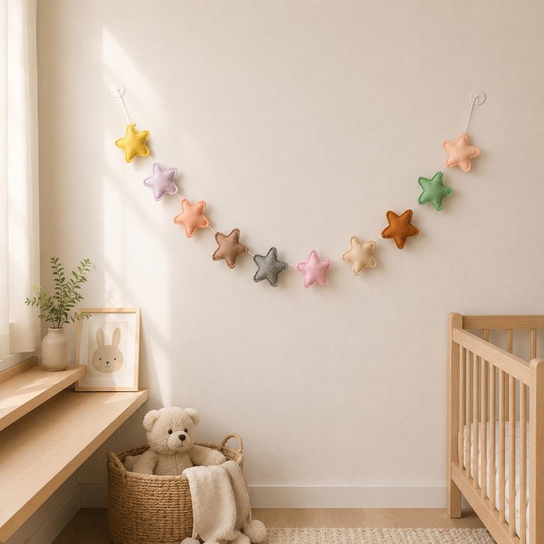 Colorful felt star garland for nursery wall decor with pastel rainbow stars hanging on string, baby room decoration above crib or shelf, soft Montessori nursery decor perfect for kids room and baby shower gift.