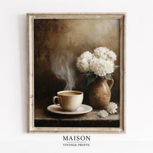Könnte beinhalten: Ein gerahmter Vintage-Druck mit einem Stillleben mit einer Tasse Kaffee, einer Vase mit weißen Blumen und dem Text "MAISON VINTAGE PRINTS". Der Kaffee dampft. Die Vase ist braun und die Blumen sind weiß. Der Druck ist in einem Holzrahmen.