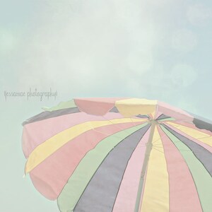 Peut inclure: Un parasol de plage ray&eacute; color&eacute; avec un sch&eacute;ma de couleurs pastel. Le parasol est ouvert et le haut est visible contre un ciel bleu clair.