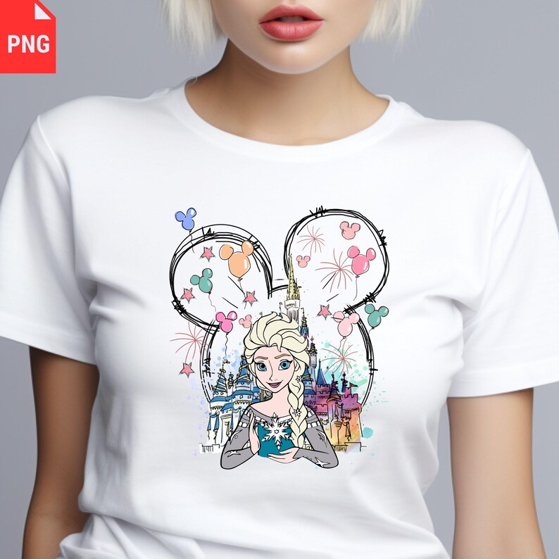May include: White t-shirt featuring a colorful illustration of a princess with a castle, fireworks, and balloons. The design is framed by a Mickey Mouse-shaped outline. The princess is wearing a blue dress and has blonde hair.