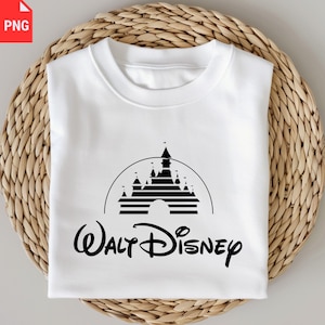 May include: White crewneck sweatshirt featuring a black graphic of a castle within a semi-circle, with the words "Walt Disney" in a script font below. The sweatshirt is folded neatly on a woven surface.