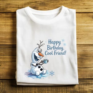 May include: White t-shirt featuring a cartoon snowman holding a mug, with the text "Happy Birthday, Cool Friend!" in blue. The snowman has a carrot nose and stick arms. The design includes snowflakes and a watercolor effect.