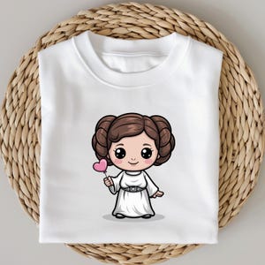 May include: White sweatshirt featuring a cartoon illustration of a character with brown hair styled in two buns, wearing a white dress and holding a pink heart-shaped lollipop. The design is centered on the front of the shirt.