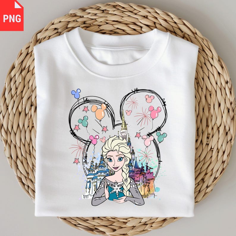 May include: White sweatshirt featuring a graphic of Elsa from Frozen, framed within a Mickey Mouse silhouette. The design includes a castle, fireworks, and colorful balloons. The sweatshirt is folded on a woven surface.