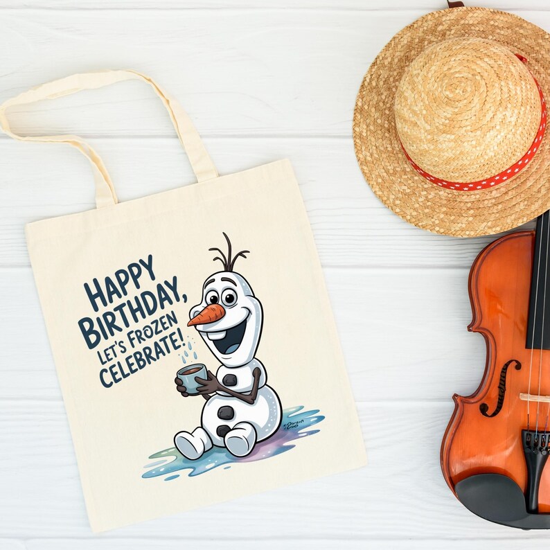May include: Cream-colored tote bag featuring a cartoon Olaf character with the text "Happy Birthday, Let's Frozen Celebrate!". A straw hat with a red ribbon and a violin are also visible.