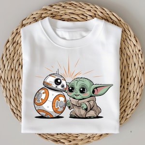 May include: White t-shirt featuring a cartoon illustration of BB-8 and Grogu (Baby Yoda). BB-8 is white and orange, and Grogu is green and wearing a tan robe. The design includes orange starburst lines behind the characters.