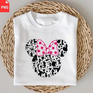 K&ouml;nnte beinhalten: Wei&szlig;es Sweatshirt mit einem Minnie-Mouse-Design. Die Silhouette ist mit schwarzen Charakterumrissen und Sternen gef&uuml;llt, mit einer rosa Schleife mit Punkten. Das Sweatshirt ist auf einer gewebten, hellbraunen Oberfl&auml;che gefaltet.