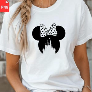 May include: White t-shirt featuring a black silhouette of a mouse head with a polka-dot bow and a castle design. The design is centered on the front of the shirt. The shirt is made of a soft, comfortable material.