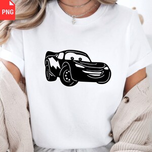 May include: White t-shirt featuring a black cartoon car design. The car has a smiling face and lightning bolt details. The shirt is made of a soft material and has short sleeves.