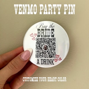 May include: A white round pin with the text "VENMO PARTY PIN" at the top. The pin says "Buy the BRIDE A DRINK" with a QR code in the center. Red heart graphics are scattered around the pin. The text "CUSTOMIZE YOUR HEART COLOR" is at the bottom.