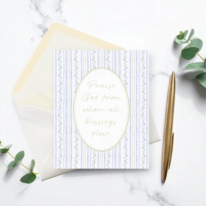 May include: A greeting card with the text "Praise God from whom all blessings flow" in an oval frame. The card has a striped pattern in blue and green. A gold pen and envelope are also in the image.