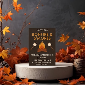 Könnte beinhalten: Eine dunkelbraune Einladungskarte mit dem Text "Join us for Bonfire & S'mores" und Veranstaltungsdetails. Die Karte zeigt eine Lagerfeuergrafik mit Marshmallows an Stöcken. Herbstblätter und Zweige mit orangefarbenen und gelben Blättern umgeben die Karte.