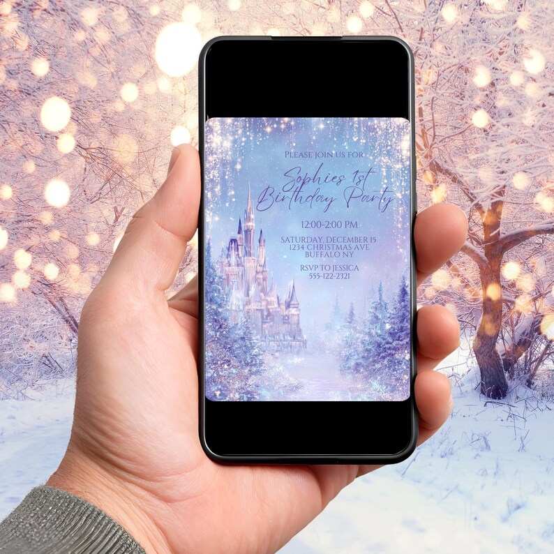 May include: A smartphone displays a birthday party invitation. The invitation features a winter wonderland scene with a castle, trees, and falling snow. Text reads "Sophie's 1st Birthday Party" with event details. The background is a snowy landscape.