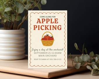 Op de afbeelding: Een crème-kleurige uitnodigingskaart met een geschulpte rand, die een appelplukevenement aankondigt. De kaart bevat de tekst "Come Along For Apple Picking" in bruin, met een mand met appels. Datum, tijd, locatie en RSVP-gegevens zijn inbegrepen.