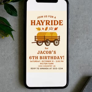Puede incluir: Un tel&eacute;fono inteligente muestra una invitaci&oacute;n de cumplea&ntilde;os con el texto "Join us for a Hayride" en marr&oacute;n. La invitaci&oacute;n presenta un carro con balas de heno y dice "&iexcl;6&ordm; Cumplea&ntilde;os de Jacob!" con detalles del evento.