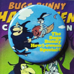 May include: A round, blue button featuring Bugs Bunny and a witch from the Bugs Bunny Howl-oween Special. The button has a cartoon image of Bugs Bunny riding a broom with a jack-o'-lantern and a witch flying in the sky. The text "The Bugs Bunny Howl-oween Special" is also on the button.