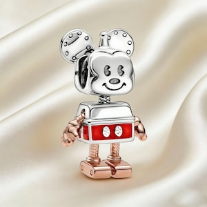 Może przedstawiać: Srebrny i czerwony charms robota Myszki Miki. Charms przedstawia głowę Myszki Miki z okrągłymi uszami i uśmiechniętą twarzą. Korpus jest czerwony z dwoma białymi okręgami, a ramiona i nogi są w kolorze r&oacute;żowego złota.