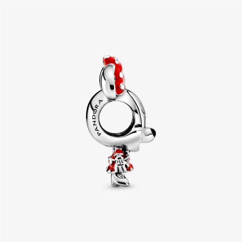 Puede incluir: Un charm plateado con dise&ntilde;o de Minnie Mouse. El charm presenta un lazo rojo con lunares blancos y un vestido rojo. La palabra "Pandora" est&aacute; grabada en el bucle del charm.
