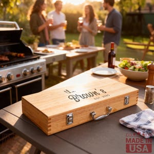 May include: A rectangular light-colored wooden carrying case with a silver metal handle and two silver latches. The top of the case features black printed text that reads "the Brown's EST. 2025" in a combination of script and sans-serif fonts.