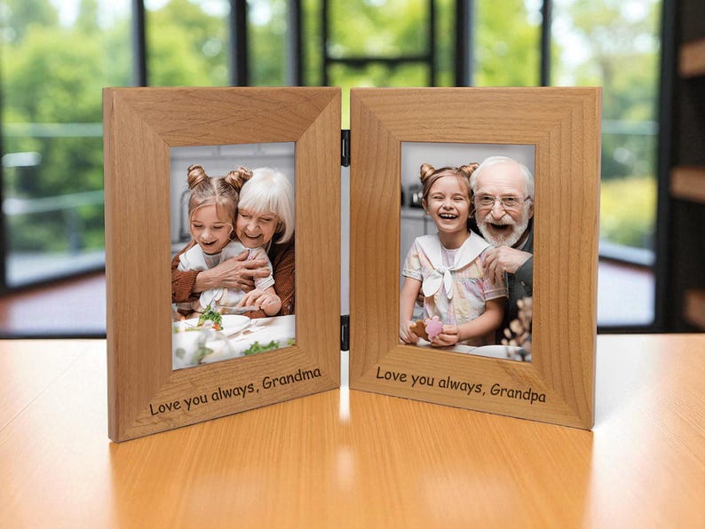 Op de afbeelding: Een houten, dubbelvouw fotolijst met twee foto's. E&eacute;n kant toont een meisje met haar oma, de andere met haar opa. De lijsten hebben de tekst "Love you always, Grandma" en "Love you always, Grandpa".