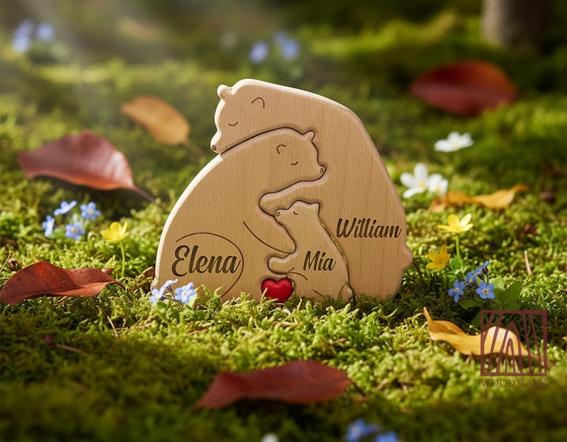 May include: Wooden bear family puzzle with the names "Elena", "Mia", and "William" engraved. The puzzle features a red heart and is set on a bed of green moss with fallen leaves and wildflowers.