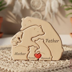 May include: A wooden bear family puzzle with the words "Father", "Mother", and children's names engraved. A red heart is placed between the two smaller bears. The puzzle is made of light-colored wood and is designed to interlock.