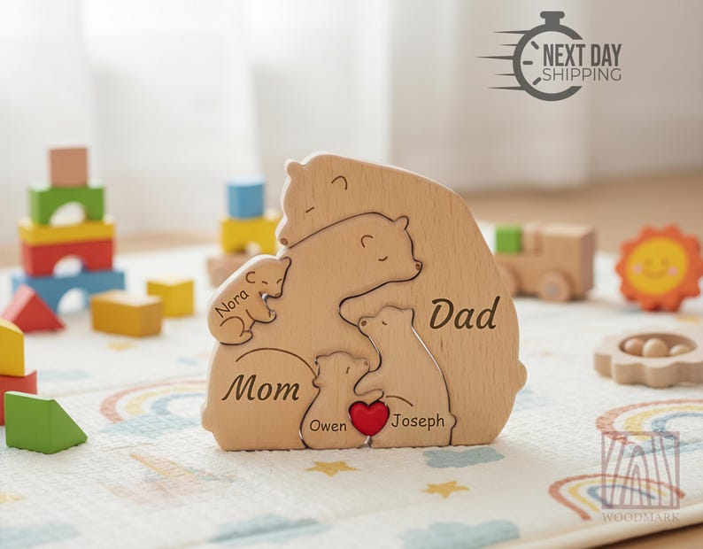 May include: Wooden bear family puzzle with the words "Mom," "Dad," and children's names. The puzzle features a red heart and is surrounded by other wooden toys. The image also includes the text "Next Day Shipping."